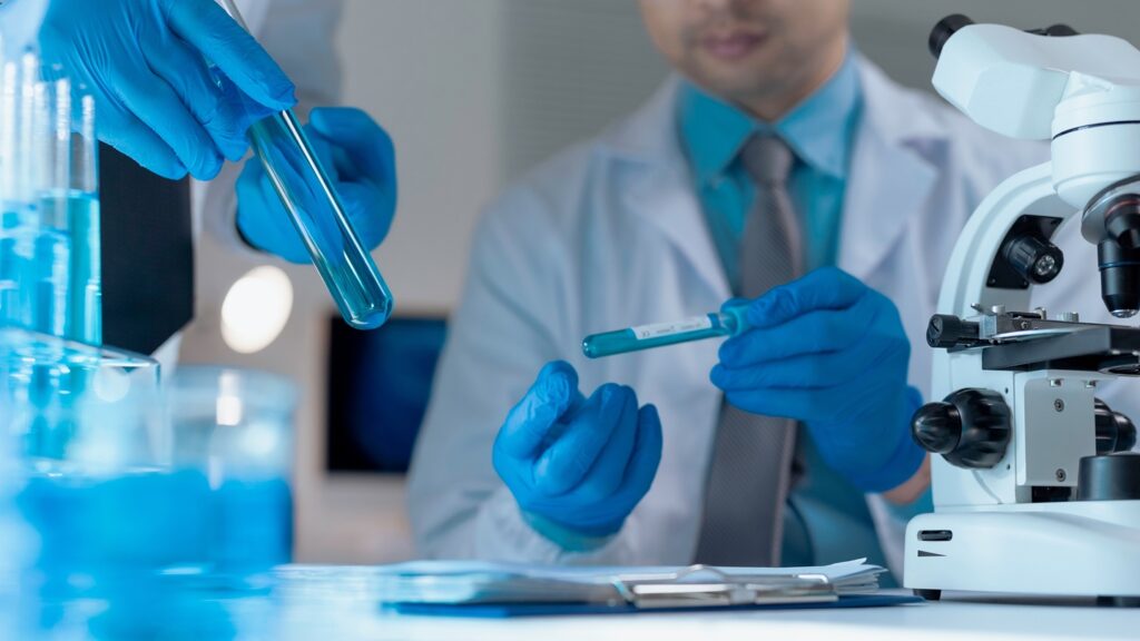 Two,Scientists,Wearing,Lab,Coats,And,Gloves,Are,Analyzing,Blue